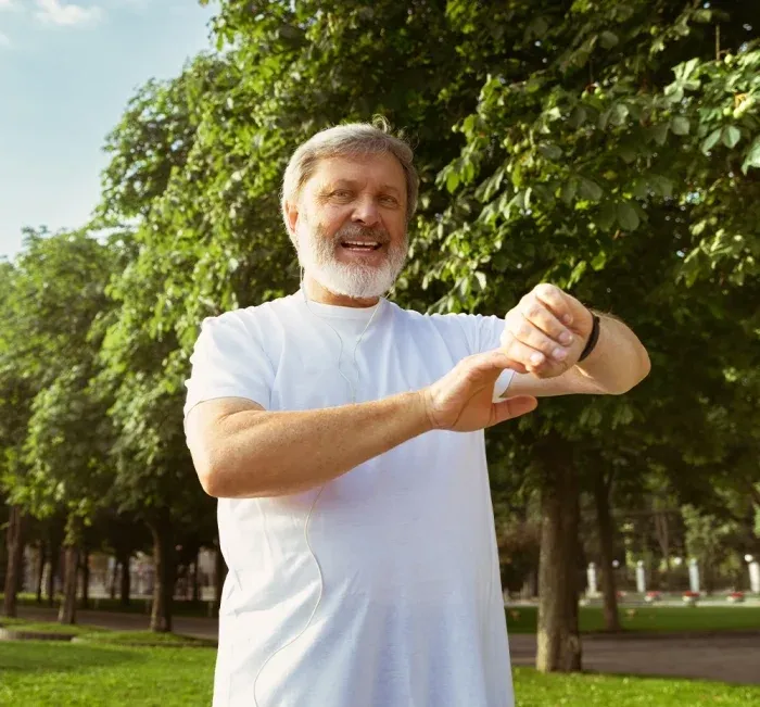 An older man in a park checks his wristwatch